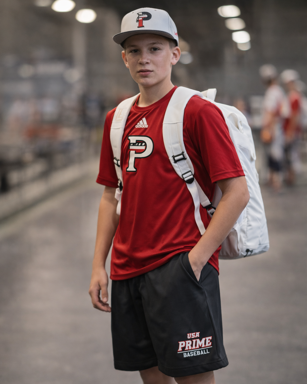 Person wearing a red shirt with a logo and black shorts with 'Prime' branding, standing in an indoor setting.