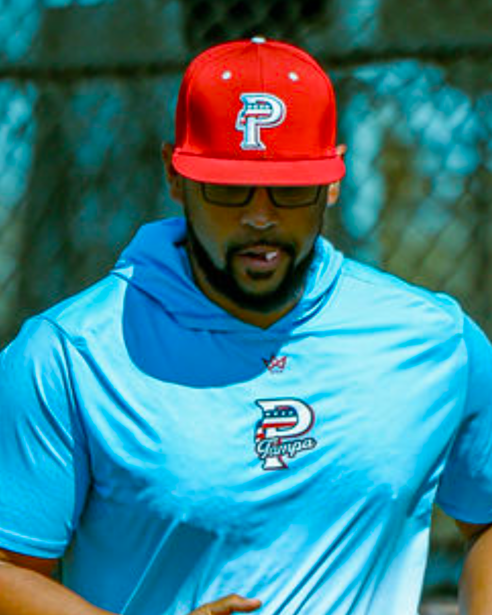 USA Prime baseball coach wearing red USA Prime game hat fitted and light blue hoodie with USA Prime logo