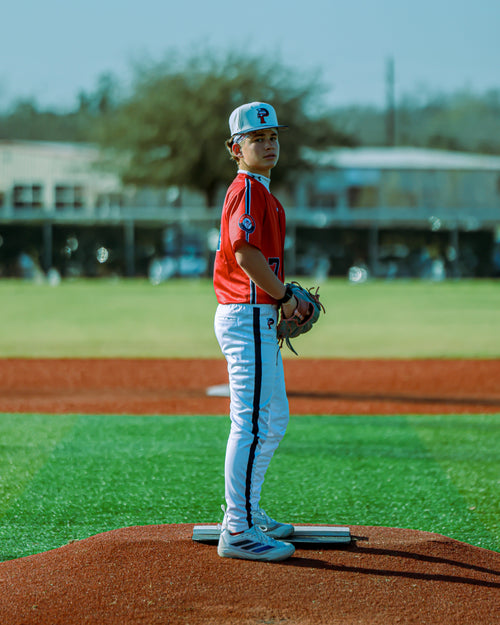 Young baseball player on a pitcher's mound with a clear sky background